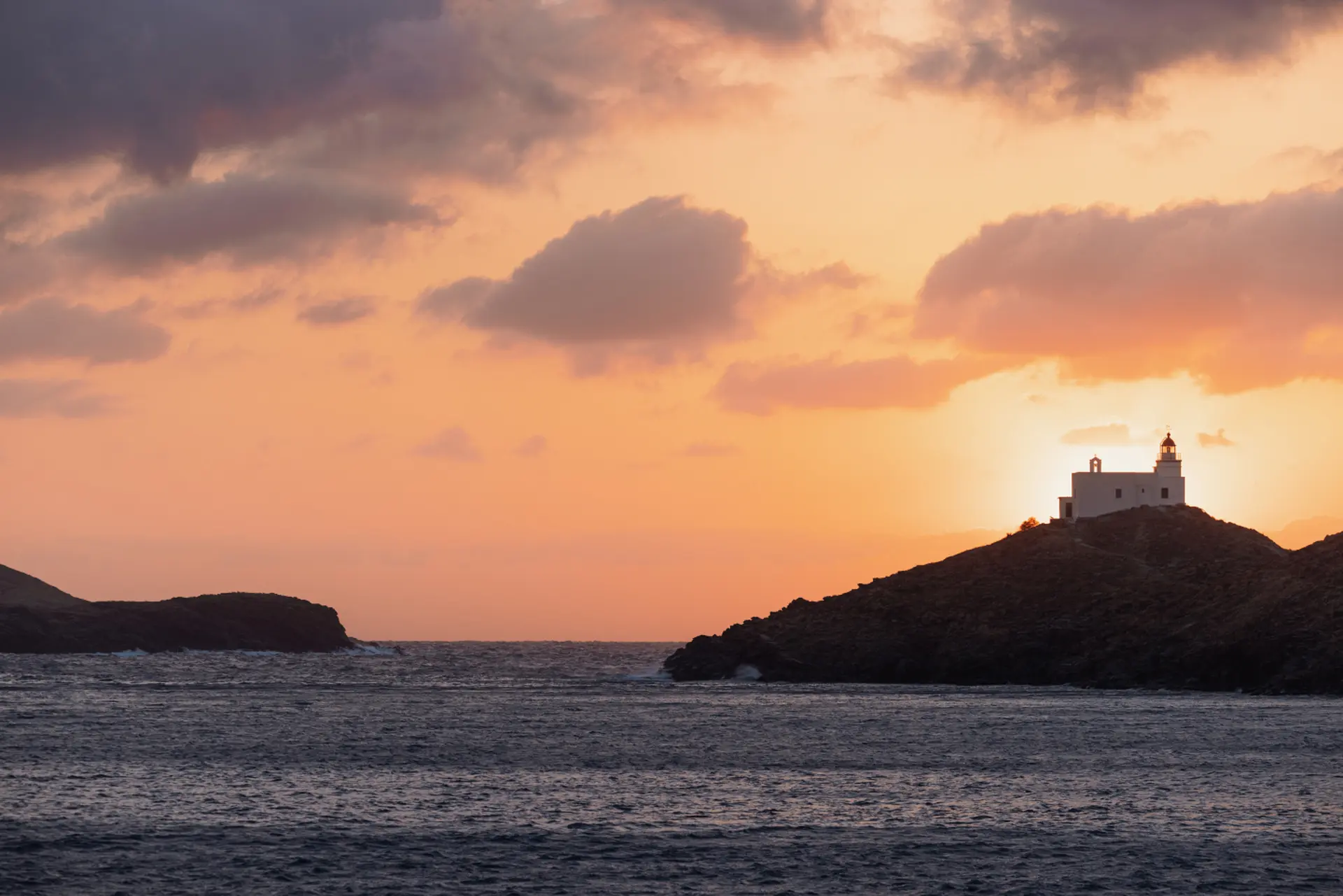 Solnedgang over kirke på klippe fra One&Only Kéa Island, Grækenland