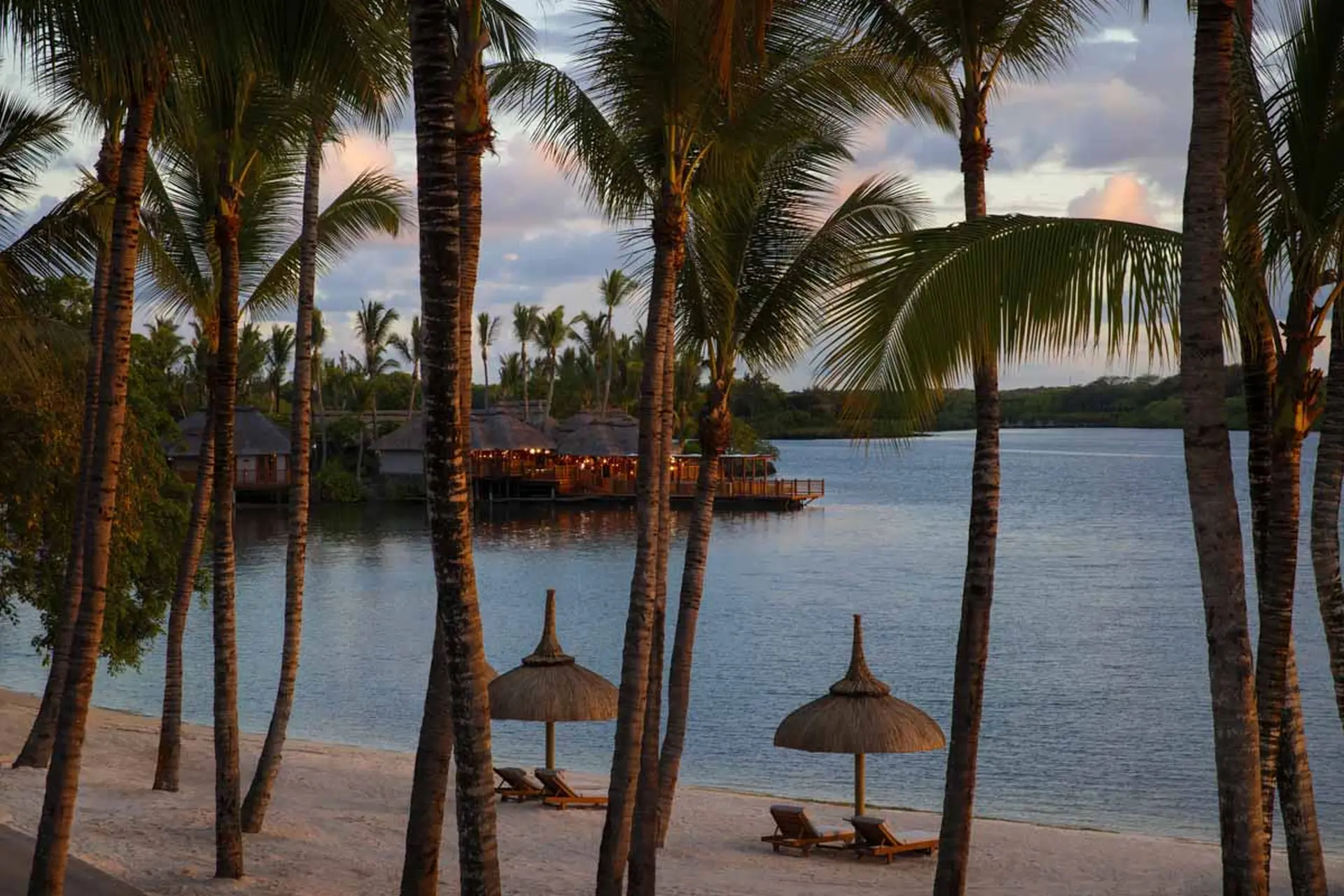 Aftenstemning ved stranden med solsenge og restaurant bag palmer på One&Only Le Saint Géran-Ocean Suite, Mauritius