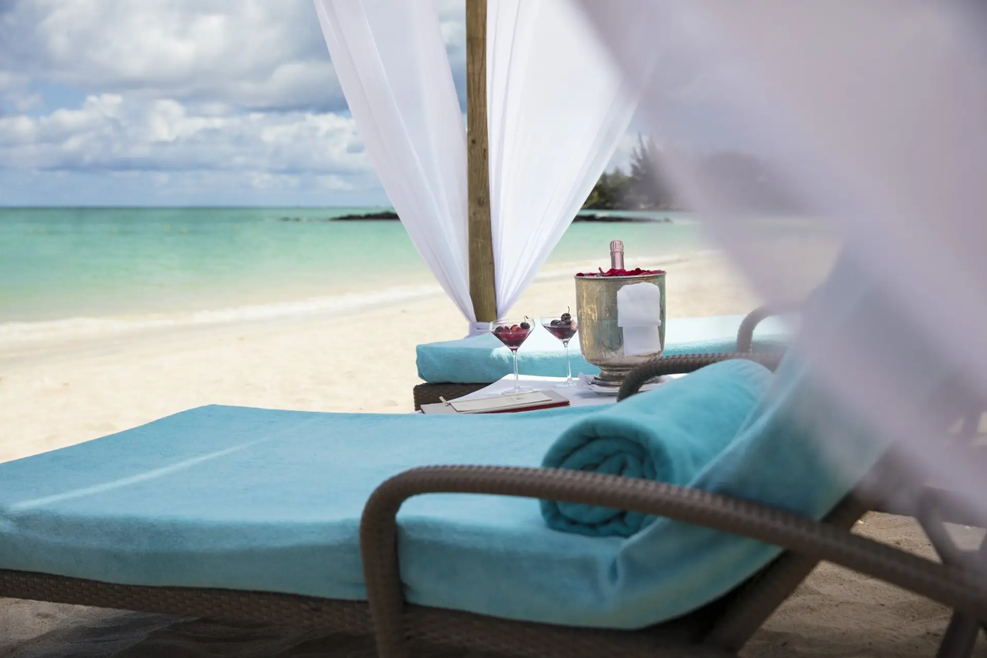 Nyd en drink i solsengen på stranden på Royal Palm Beachcomber Luxury, Mauritius