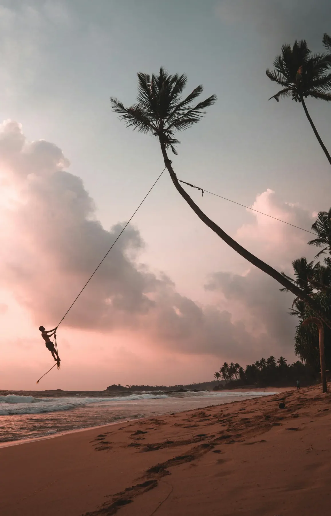En dreng svinger sig i tov over en strand på Sri Lanka